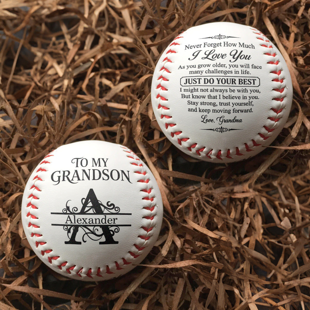 The two personalized baseballs for Alexander resting on packing straw, front and back prints both visible