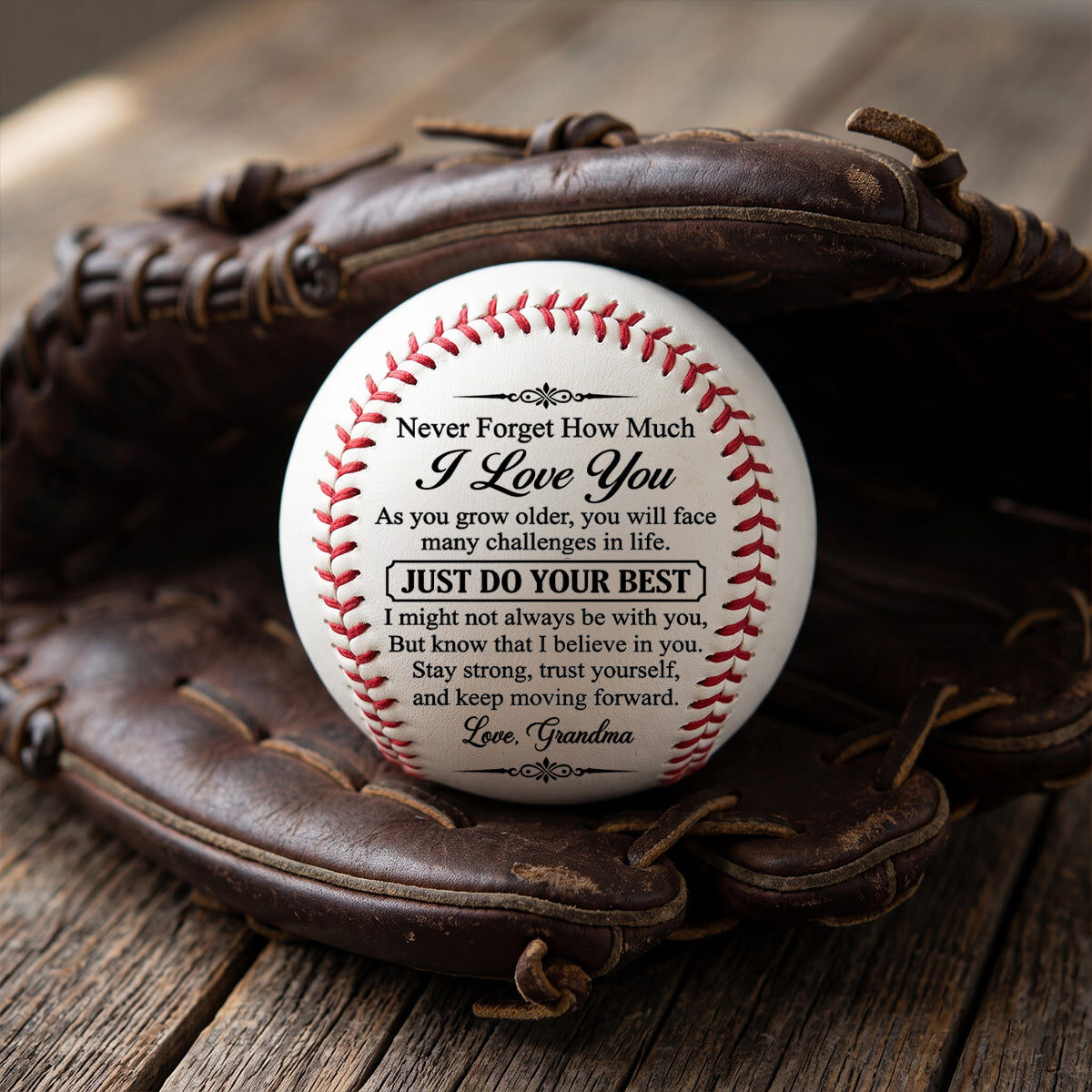 The personalized baseball for Alexander sitting in a worn leather baseball glove on a wooden table, showing the printed message and Love, Grandma